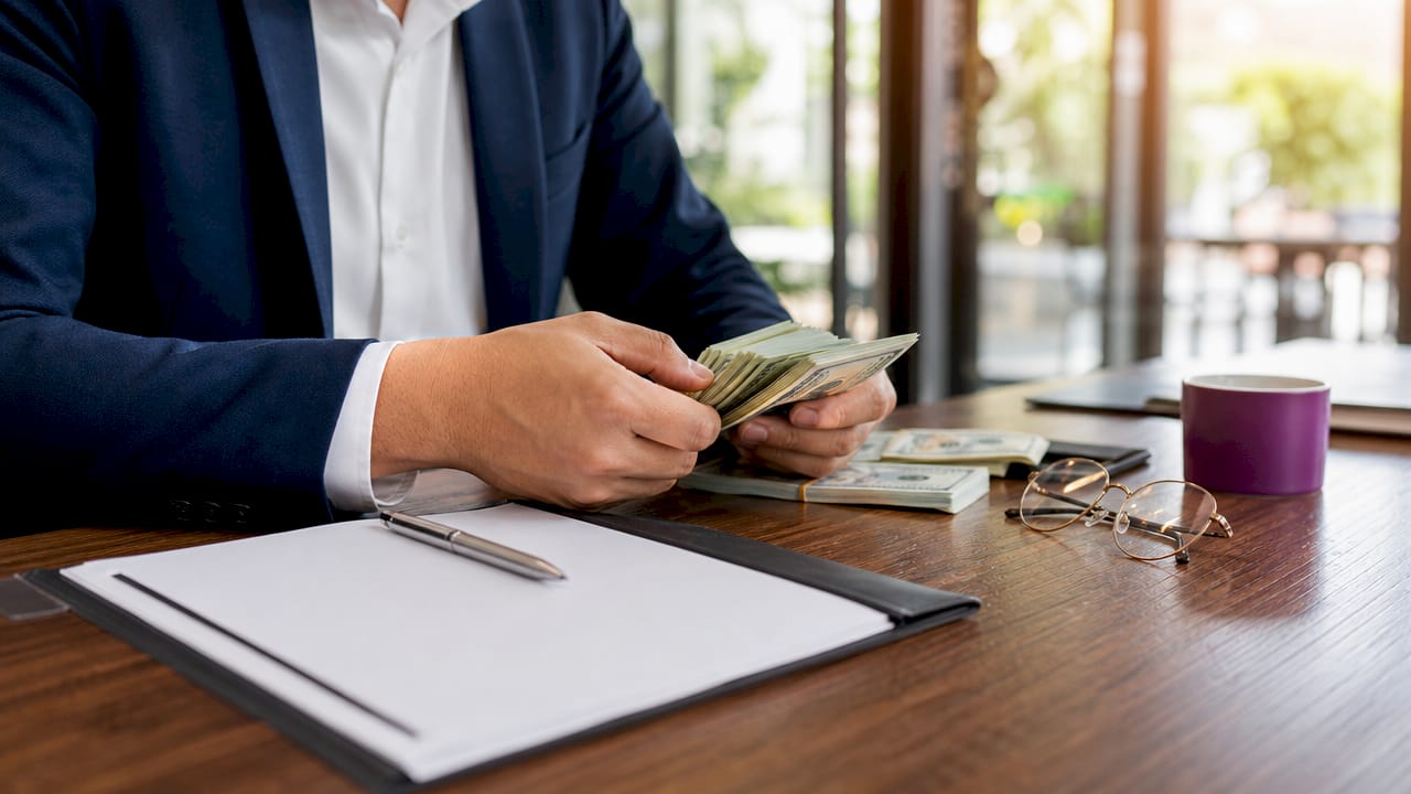 Hands counting cash near contract folder
