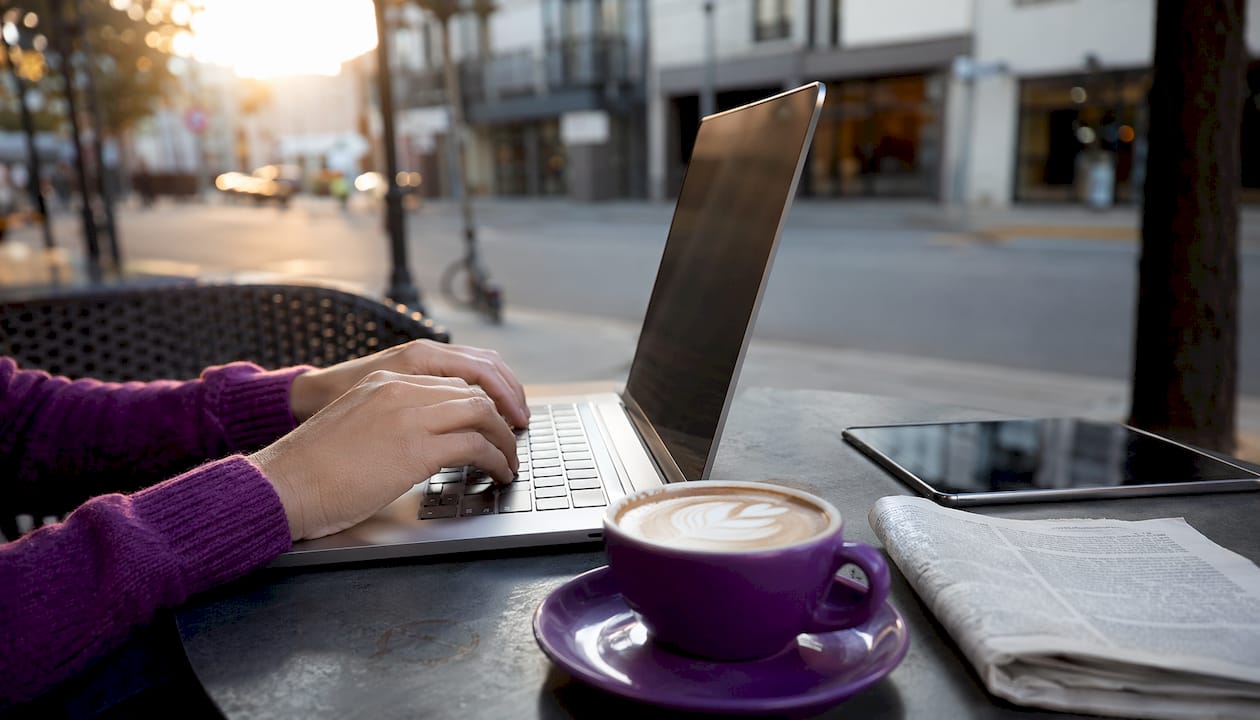 Hands typing on laptop in café setting