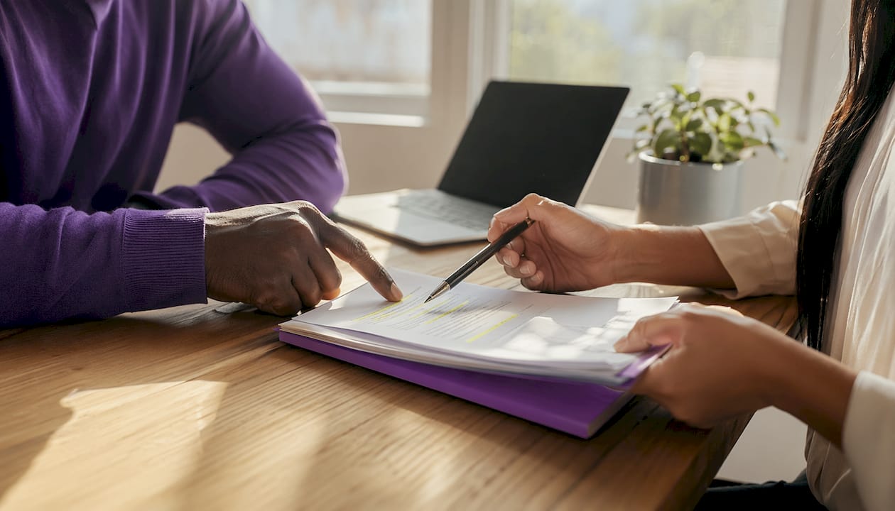 Hands exchanging pen over compliance contract