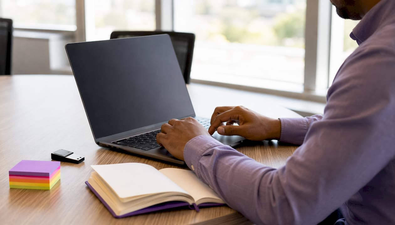 Hands typing on laptop with compliance checklist