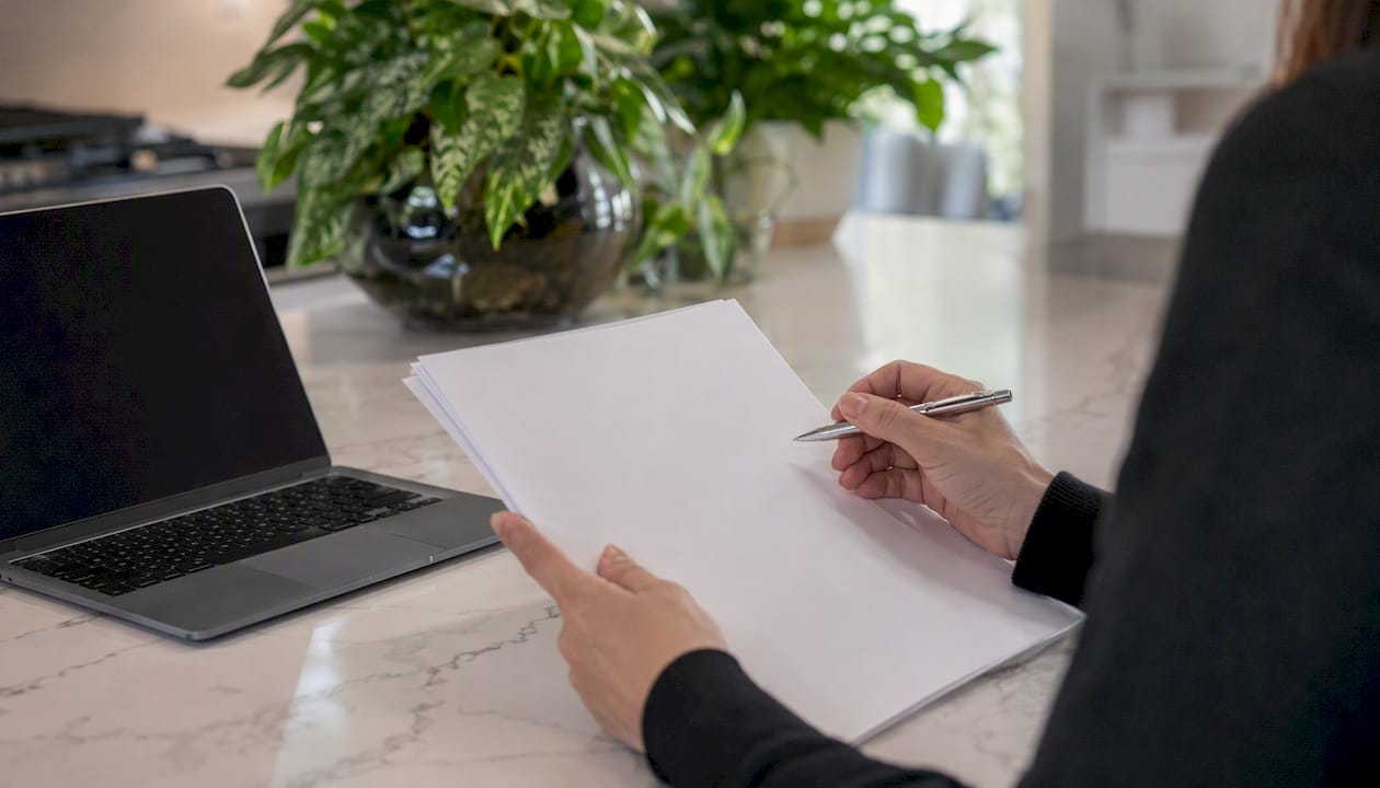 Hand with pen over paperwork and adding machine