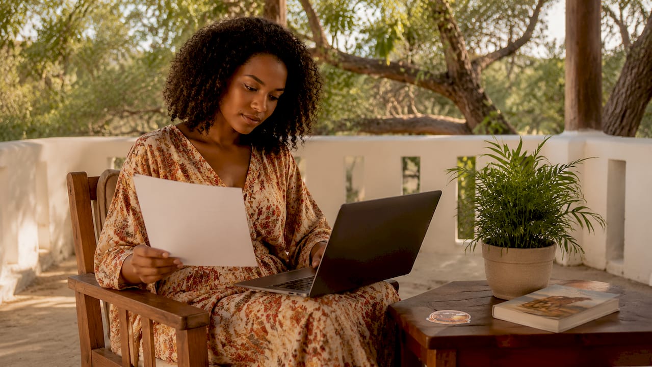 Donna che controlla i dettagli della sua assicurazione per il safari sia sullo smartphone che su alcuni documenti cartacei.Assicurazione viaggio safari Kenya