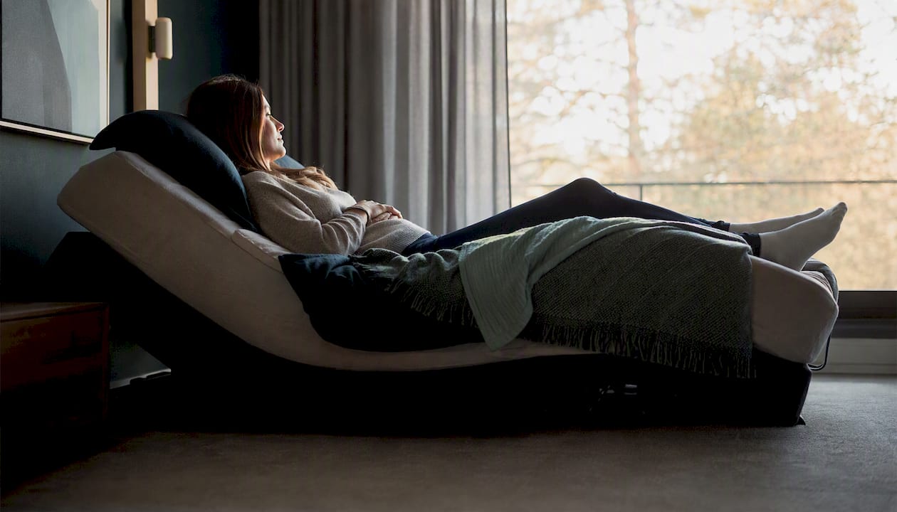 Person reclined in zero gravity bed position
