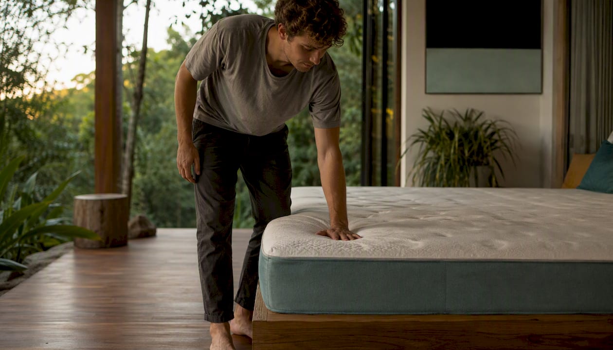 Adult assessing mattress firmness with hand