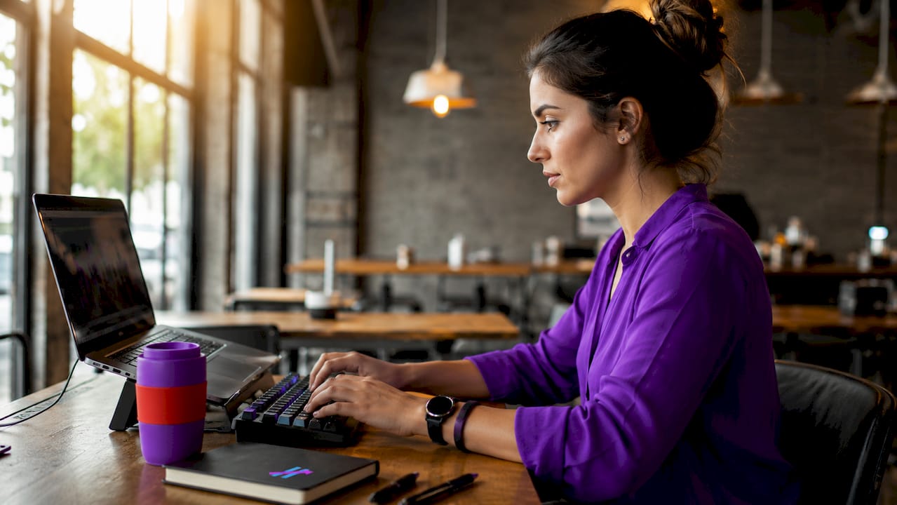 Trader typing by laptop with trading charts