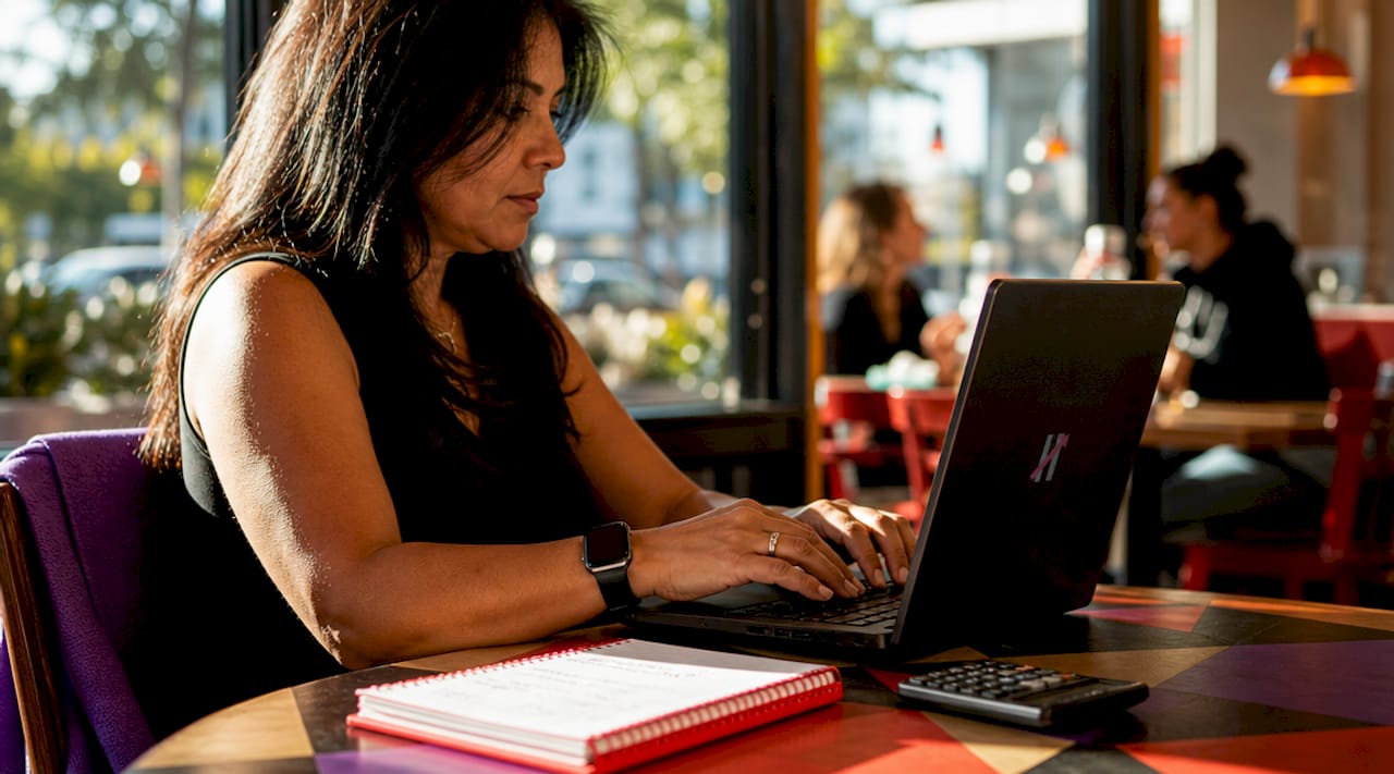 Hands typing on laptop with notes nearby