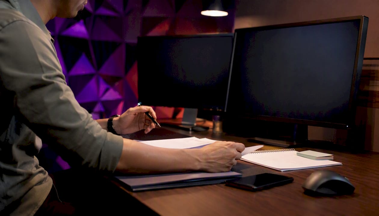 Trader hands adjusting tools by dark screens