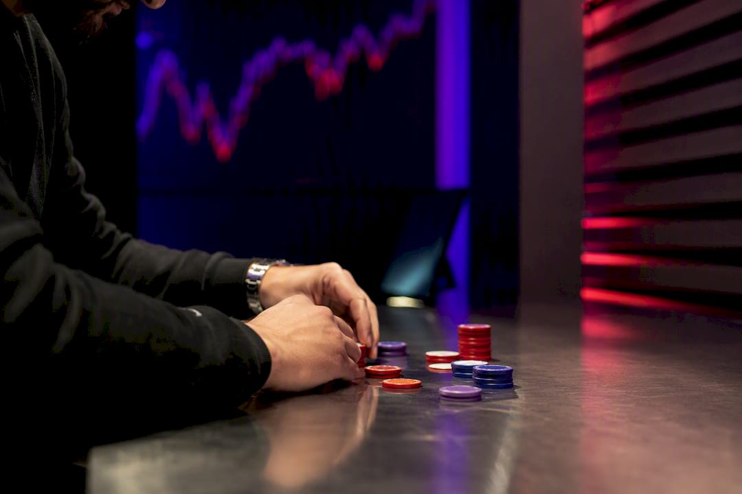 Hands sizing down trading chips on dark desk