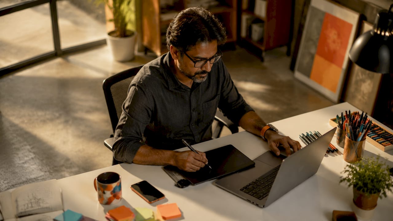 Man using laptop and drawing tablet in co-working space