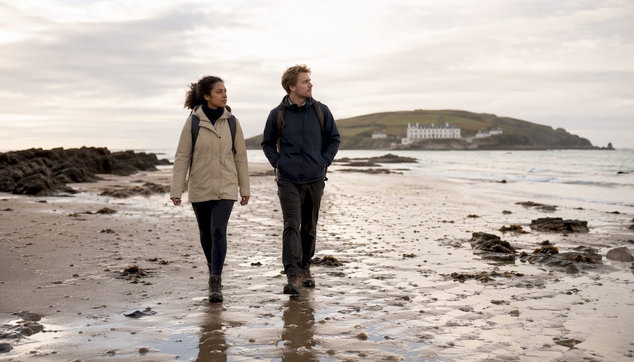 People walking the sandy causeway at low tide