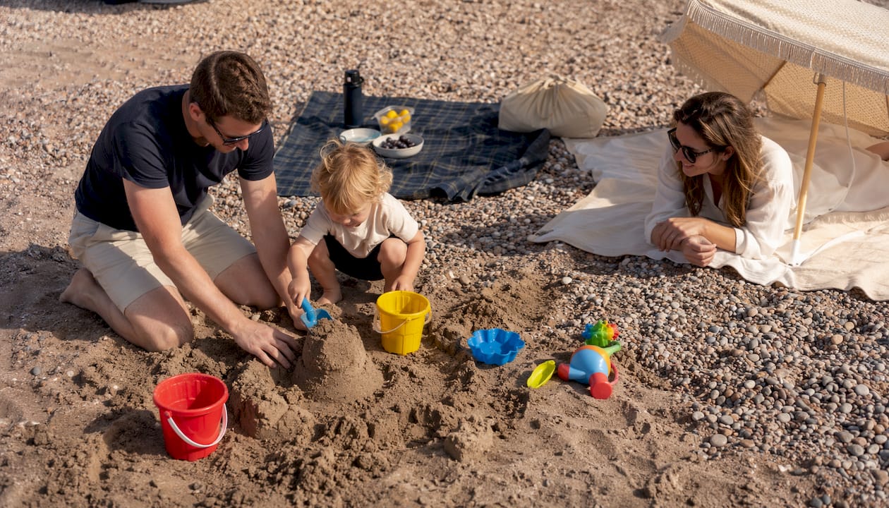 Family enjoying sandpit play on shingle beach