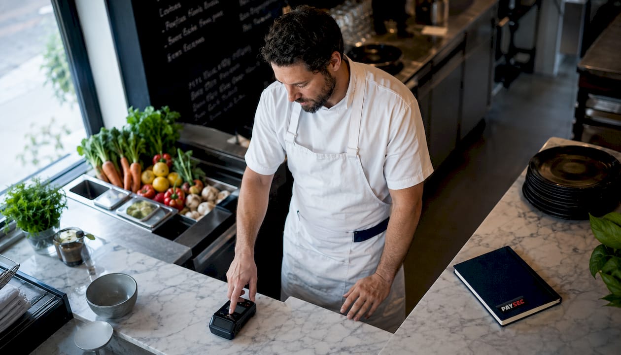 Chef with payment terminal in restaurant kitchen
