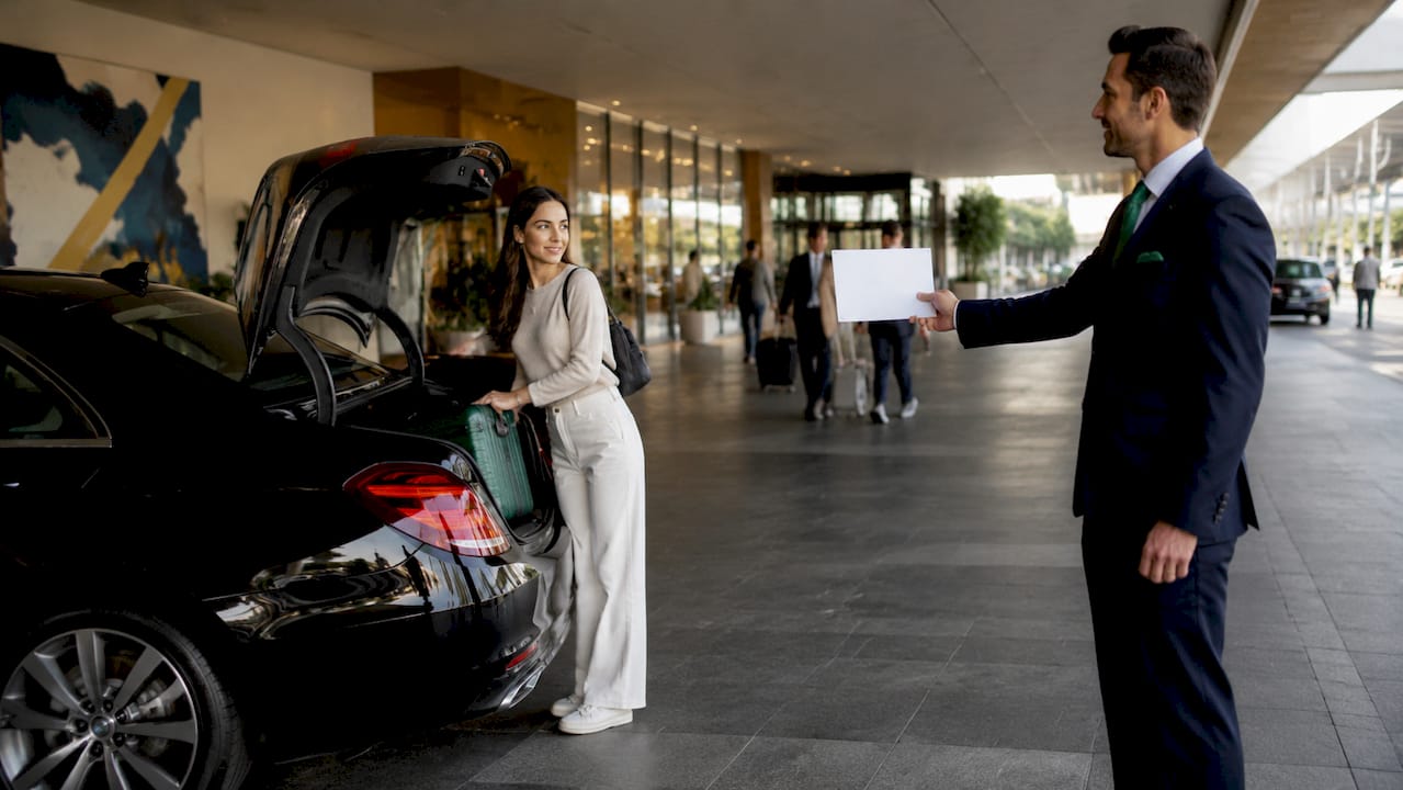 Chauffeur meeting traveler with luggage at airport
