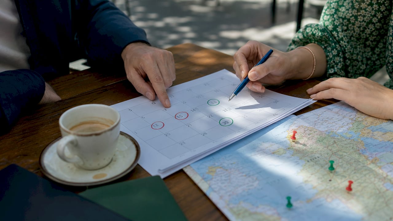 Hands coordinating travel dates on calendar