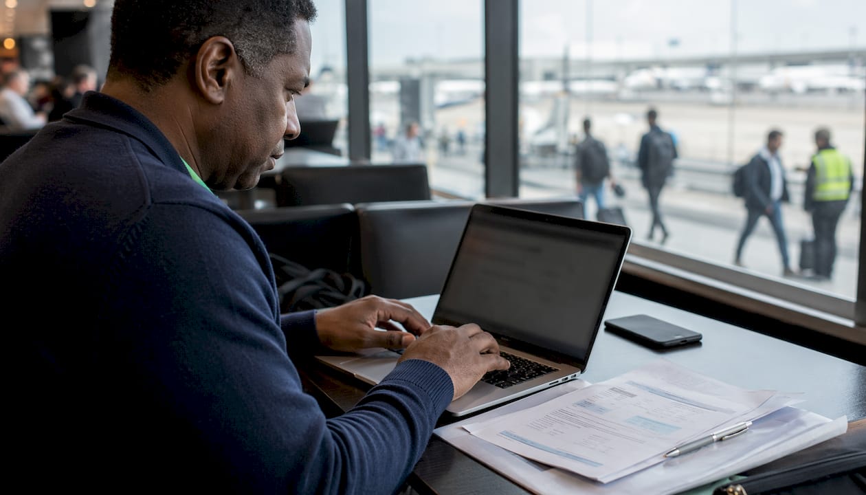 Man sending airport transfer cancellation email at lounge desk