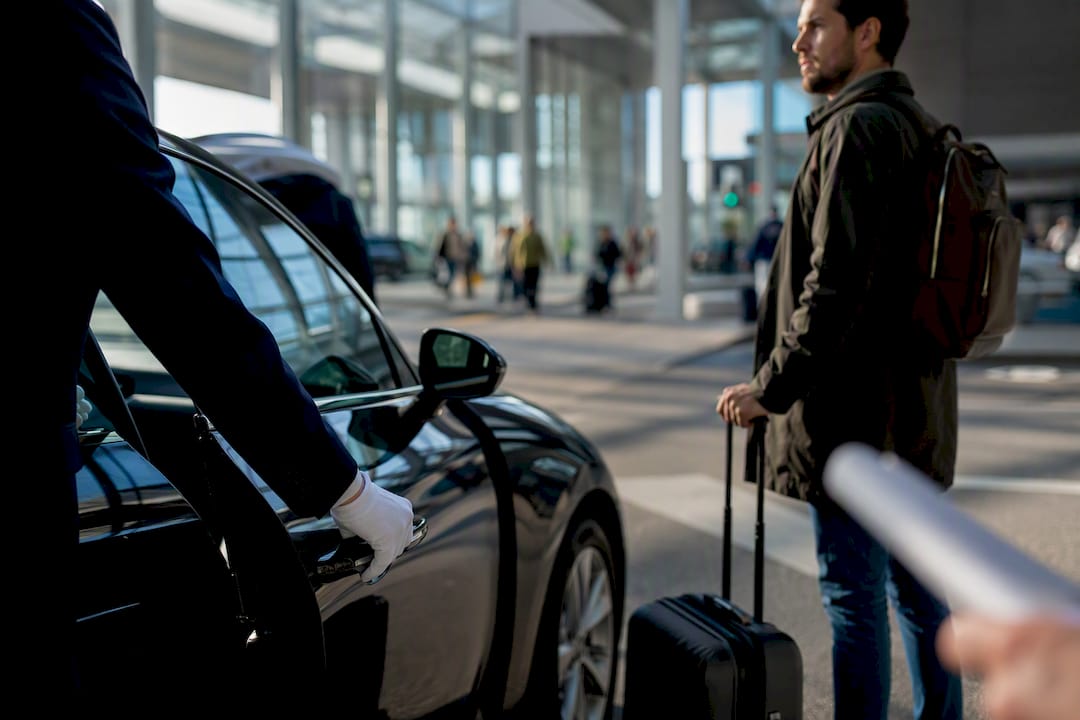 Chauffeur opening car door for traveler