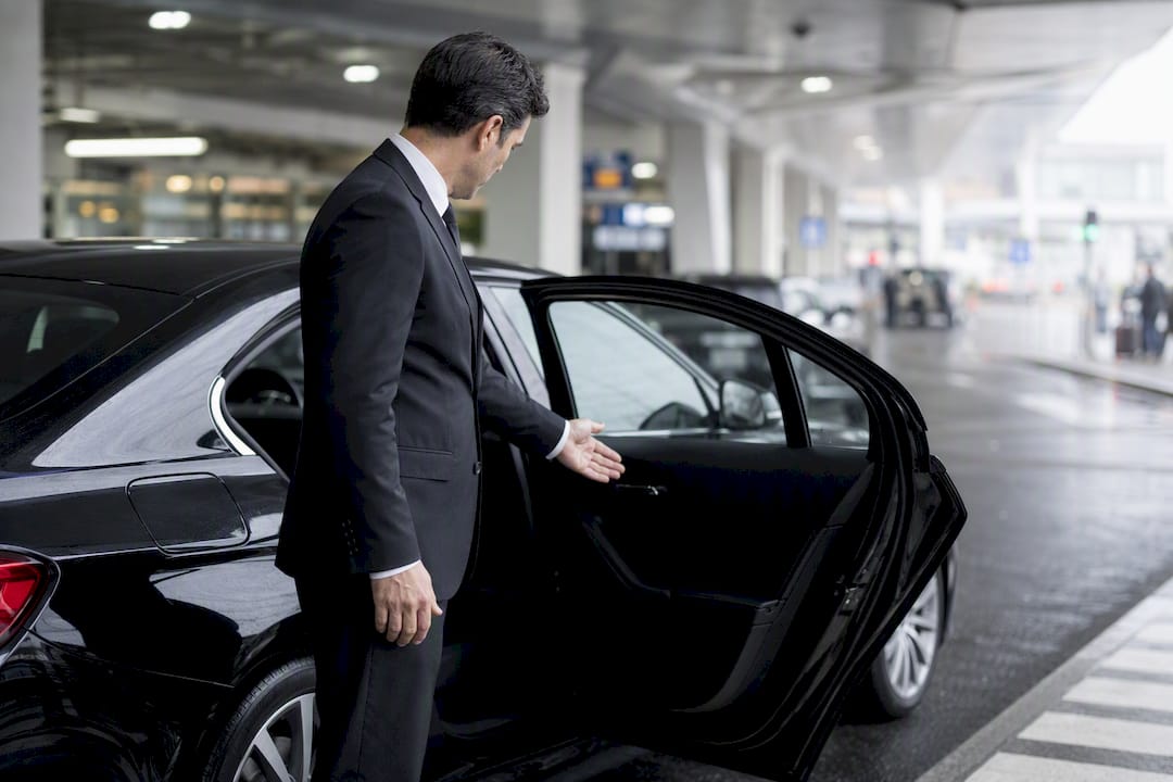 Chauffeur opening car door for private transfer