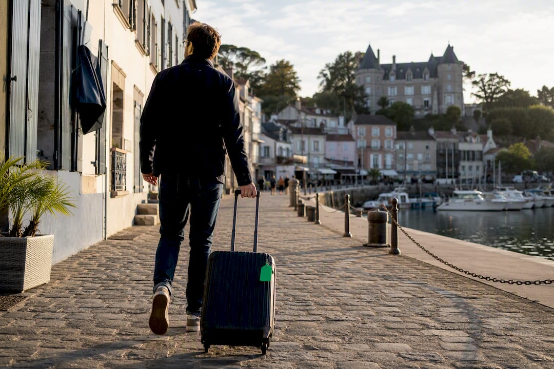 Traveler walking luggage beside Pornic harbor