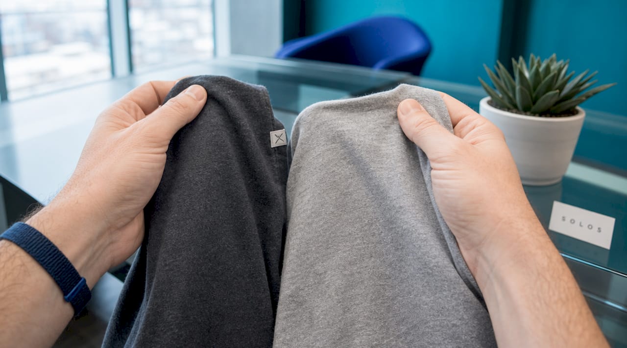 Hands comparing two cotton blend T-shirts