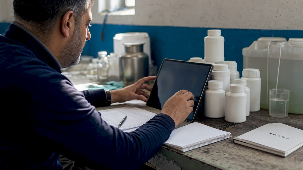 Hands reviewing chemical compliance checklist on tablet