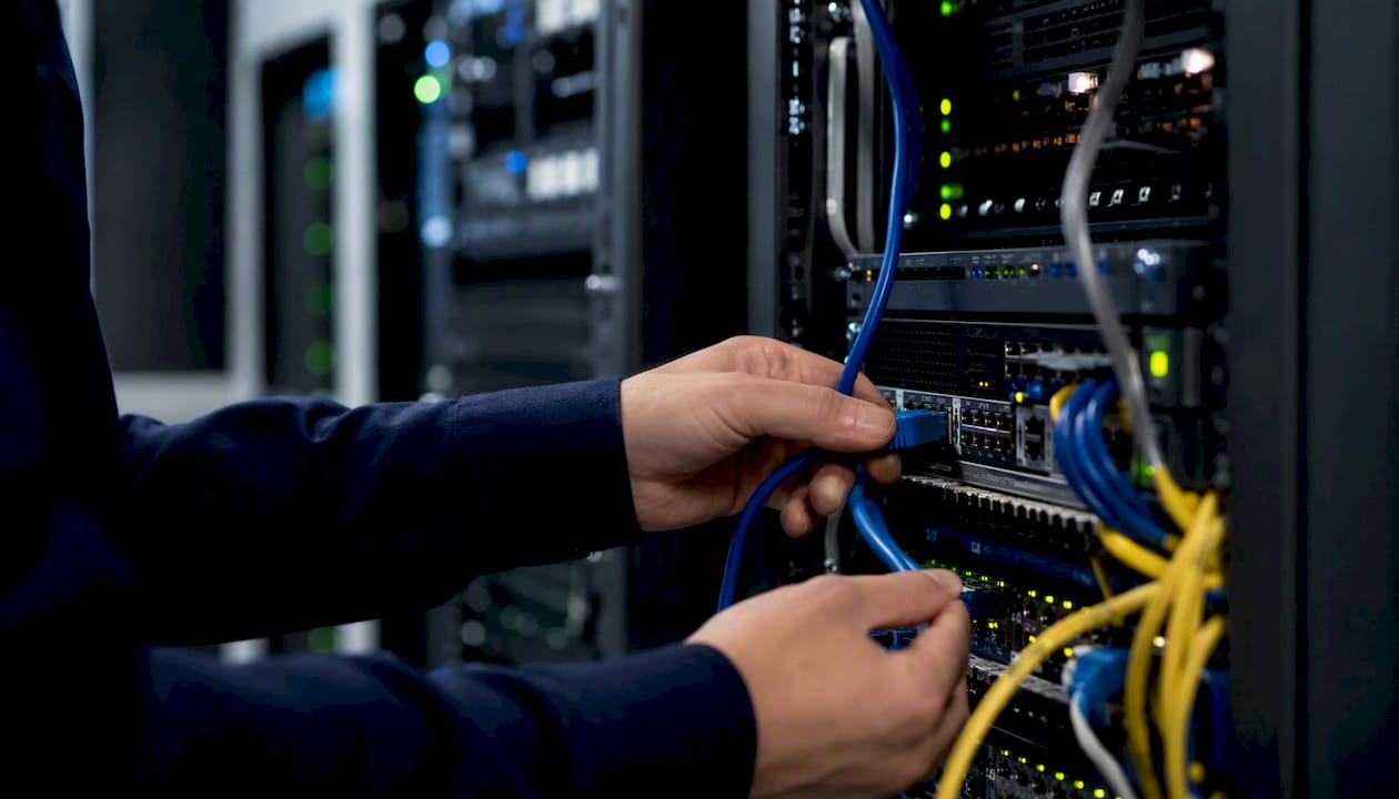 Hands connecting network cable in server room