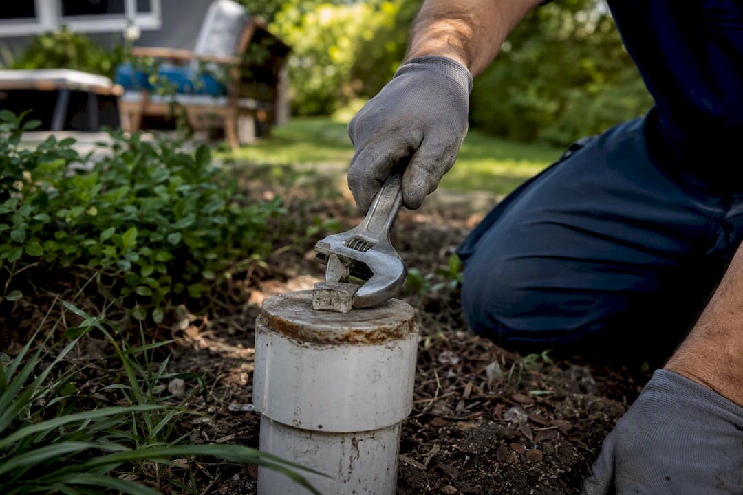 Gloved hand testing sewer cleanout cap with wrench