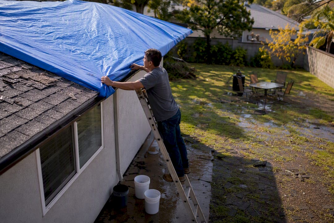 Securing blue tarp over damaged roof