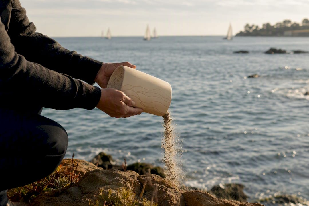 Hands scattering ashes into San Diego ocean