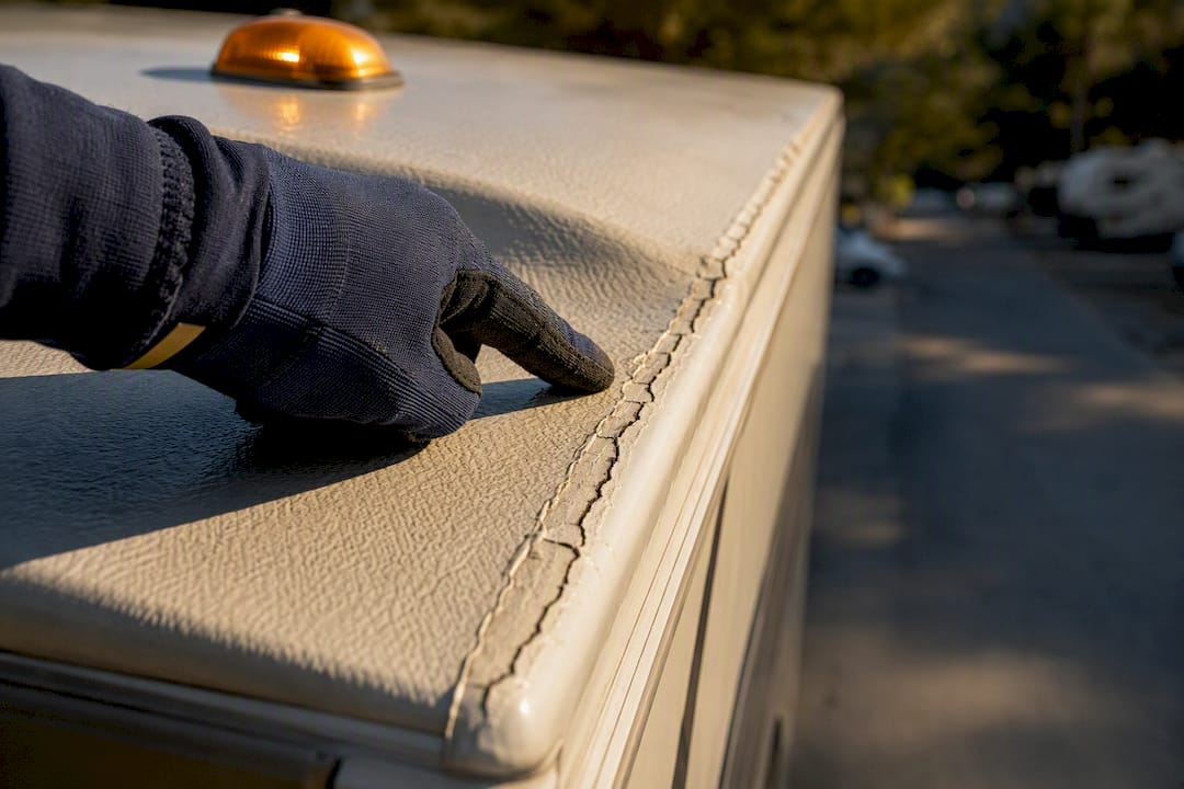Close-up inspection of cracked RV roof sealant