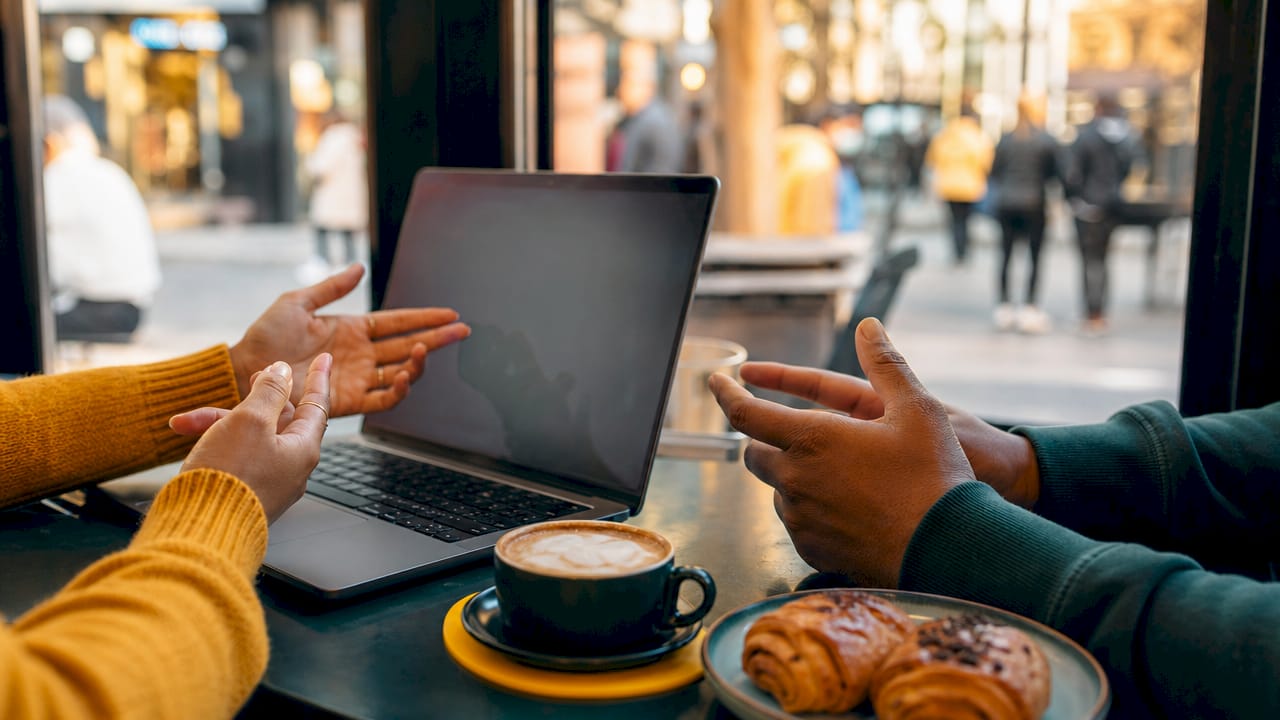 Hands poised on laptop in bright workspace near coffee