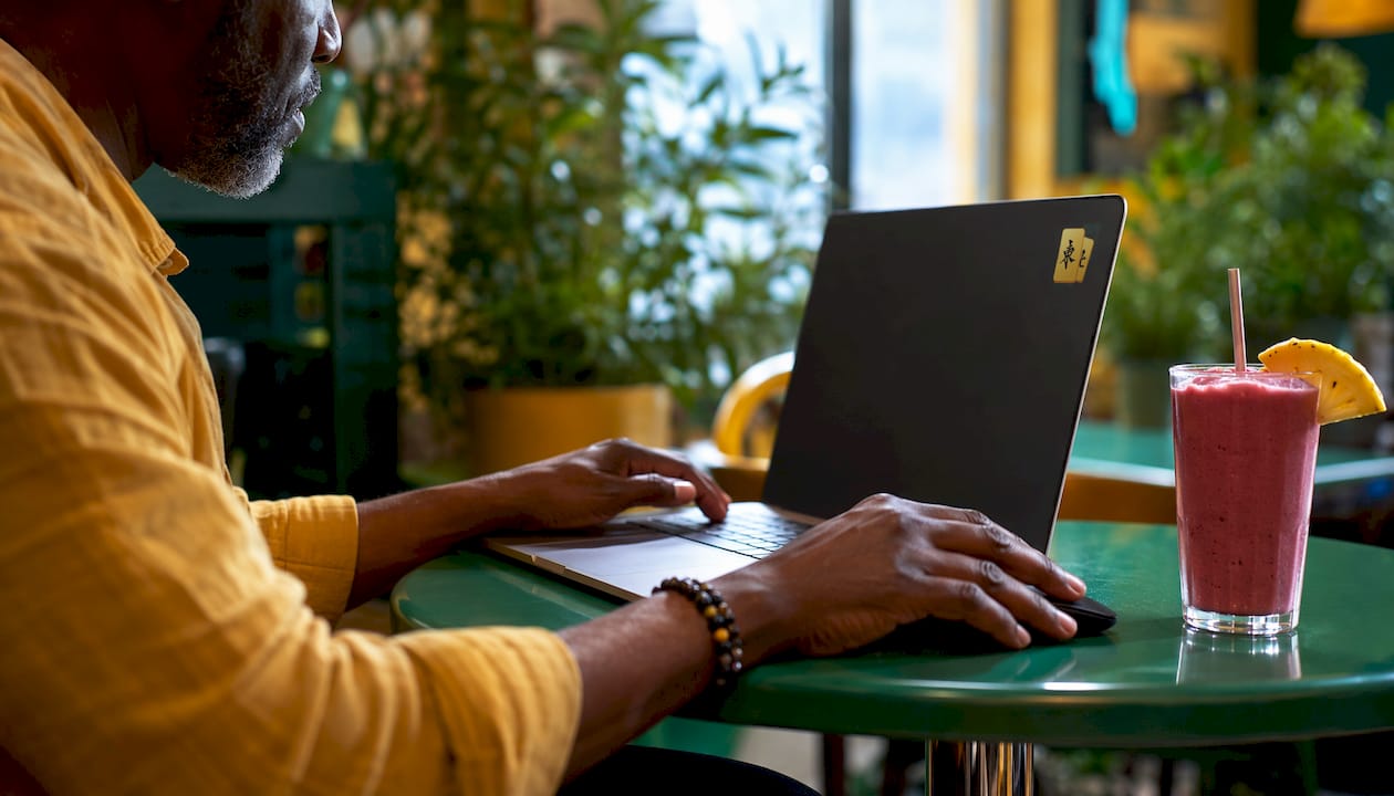 Hands using laptop and tablet to play Mahjong online