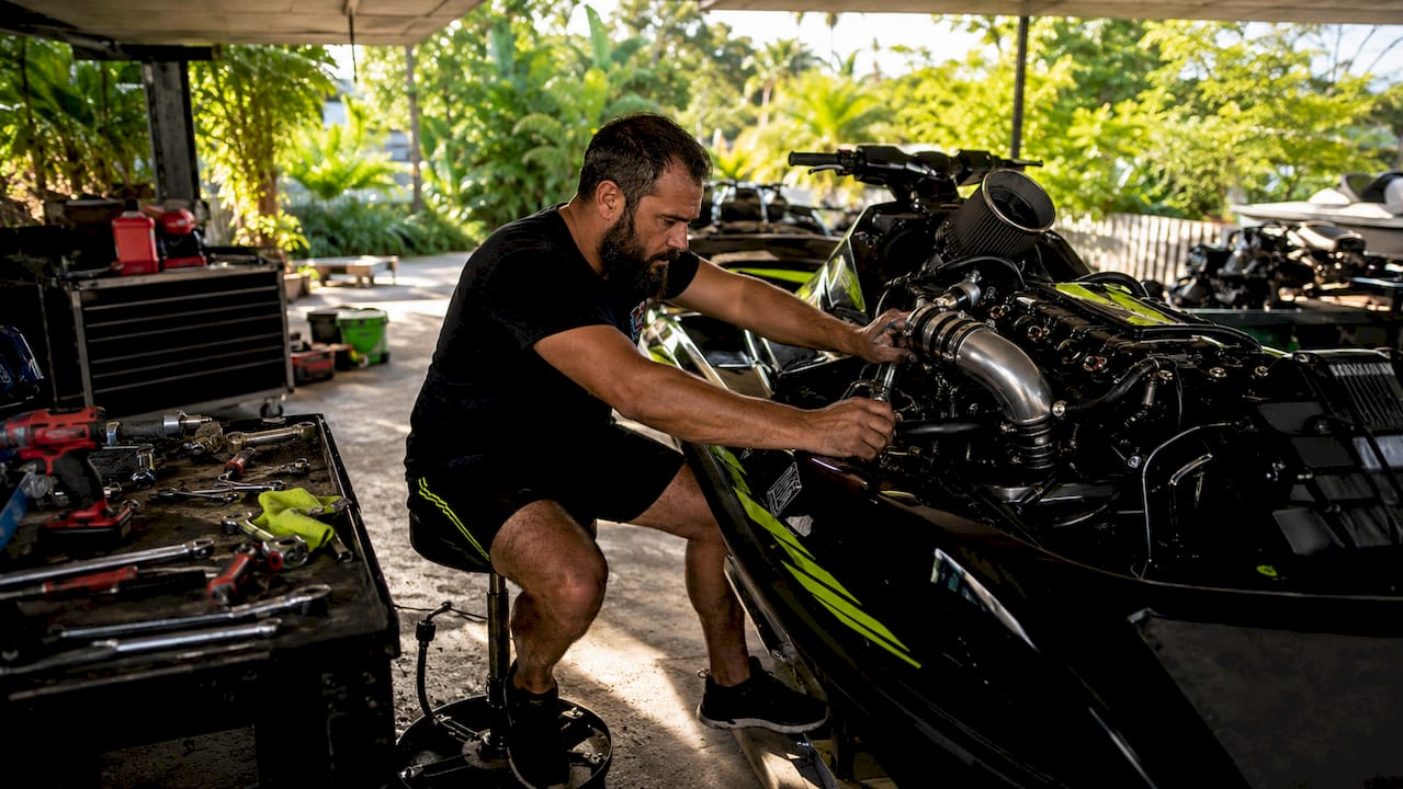 Mechanic tuning turbocharged jet ski in garage