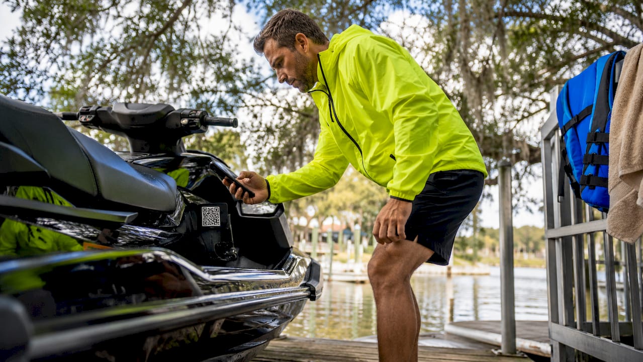 Man scanning QR code decal on jet ski for maintenance