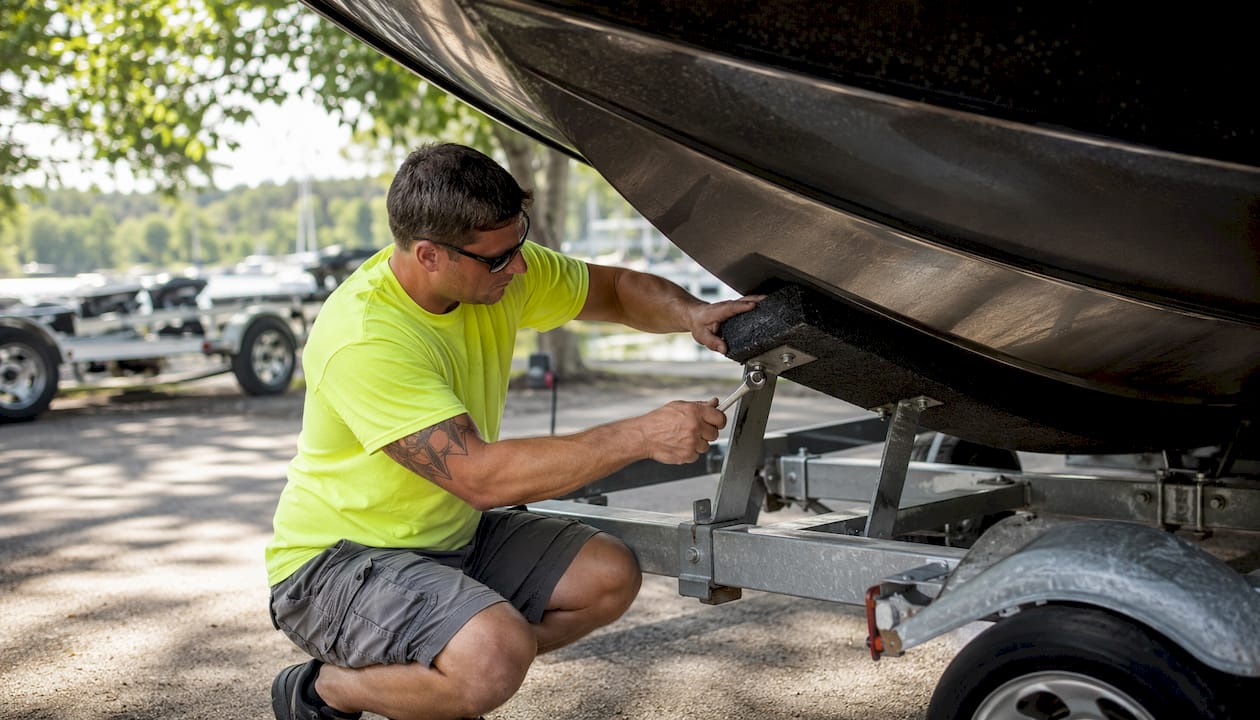 Technician adjusting trailer bunk under hull