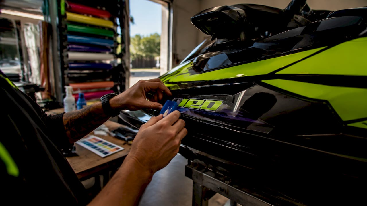 Hands applying sponsor graphic to jet ski hull