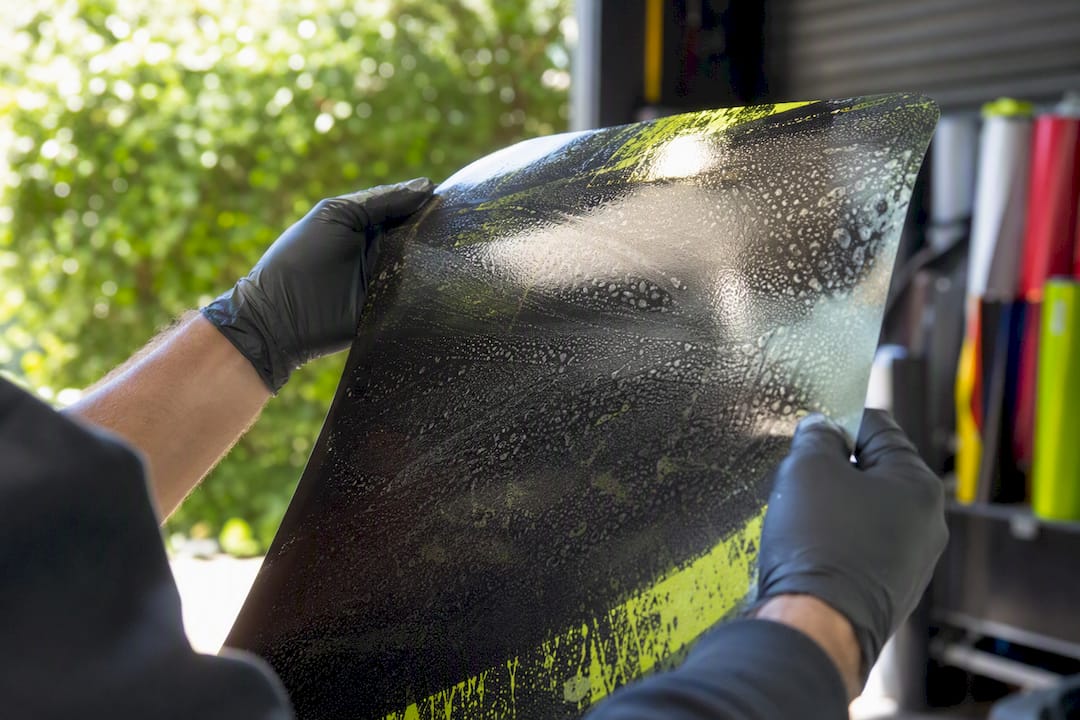 Hands inspecting laminated vinyl wrap sheet