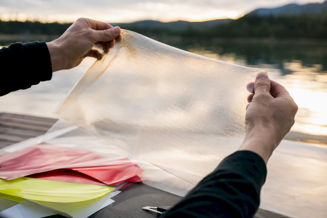 Transparent protective overlaminate film held stretched