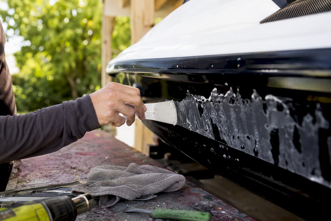 Plastic scraper gently lifting adhesive