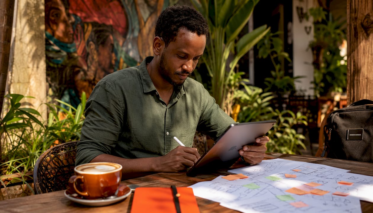 Man writing AI content notes on tablet in café