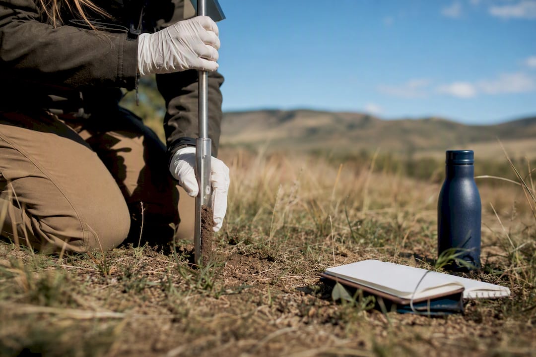 Gloved hand collecting soil sample on conserved land