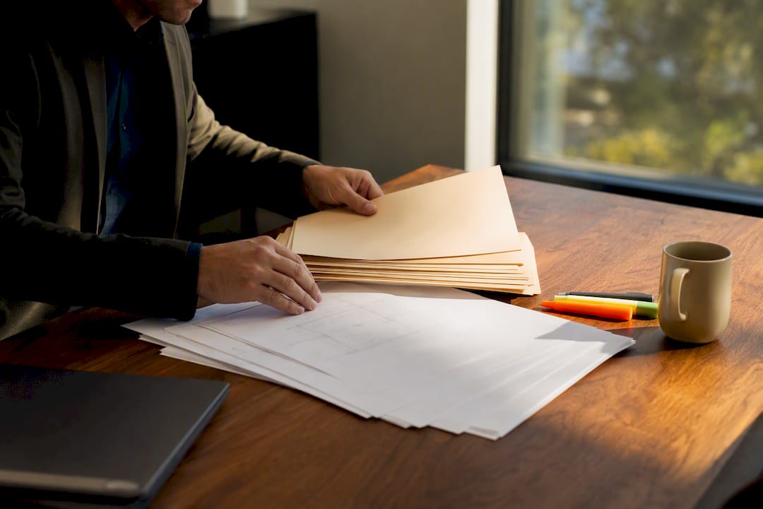 Hands organizing permit folders on table