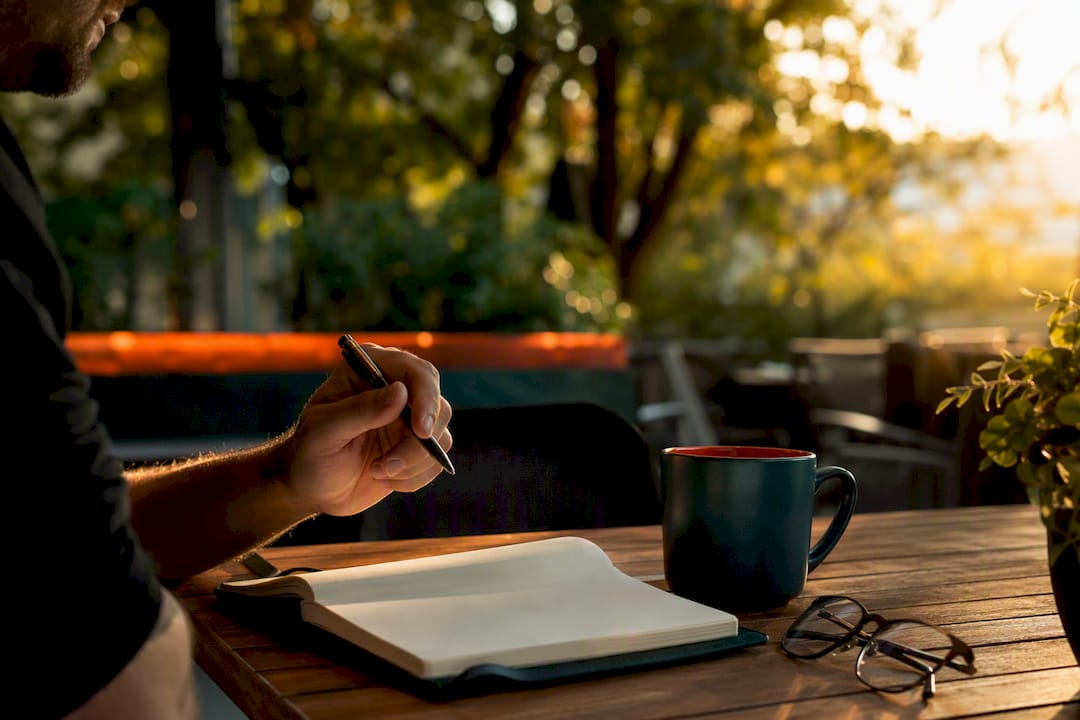 Writer's hand pausing thoughtfully over blank notebook