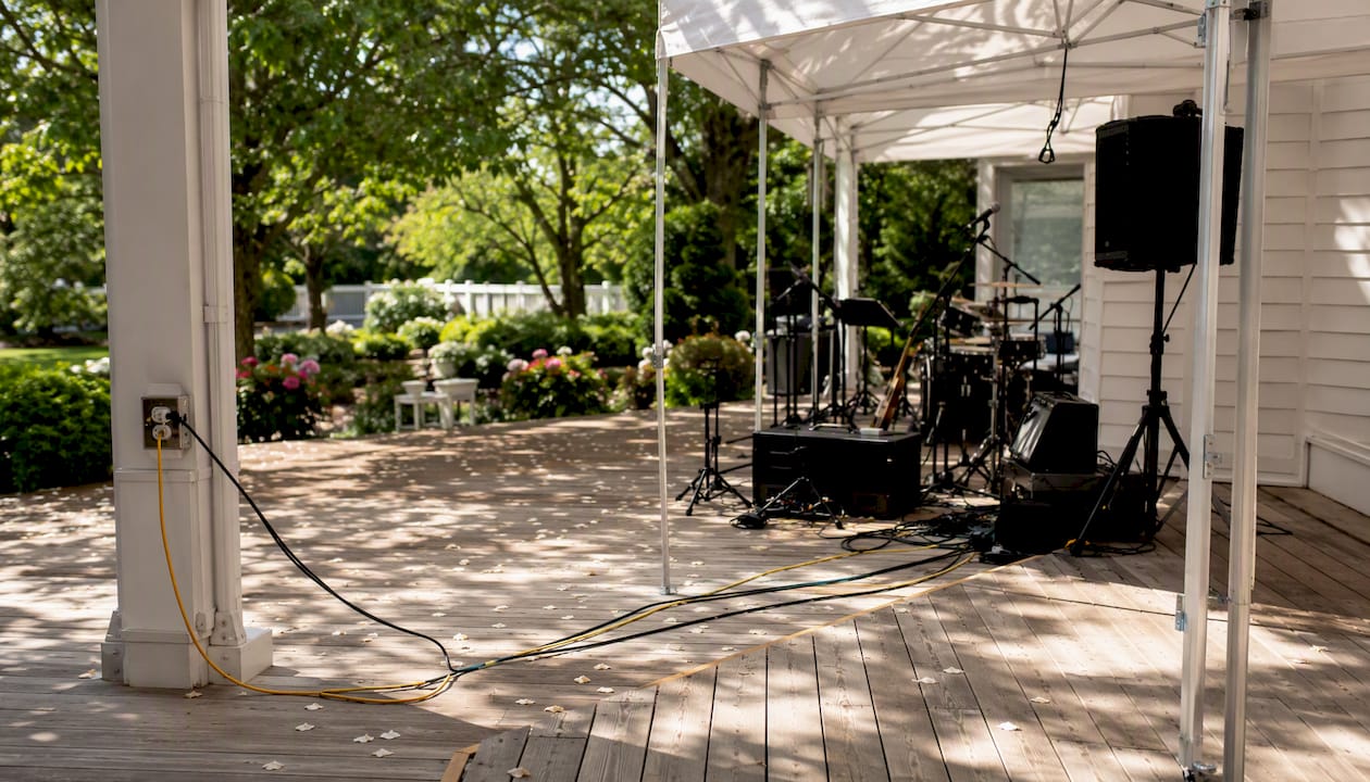 Covered backup band setup area at outdoor wedding