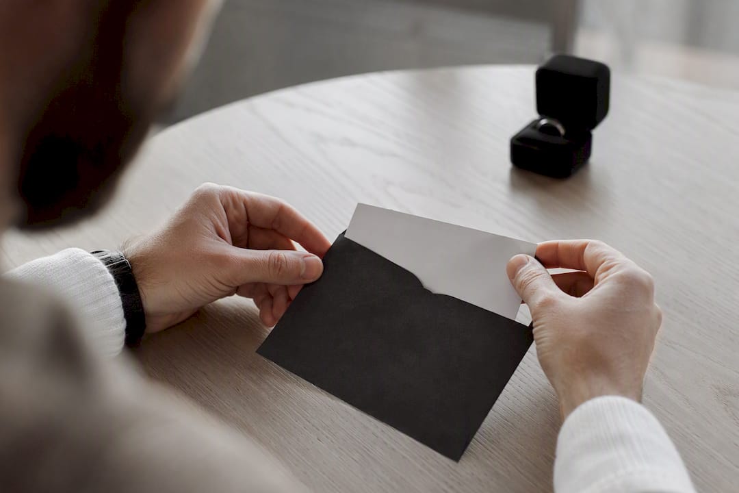 Hands placing wedding band deposit into envelope