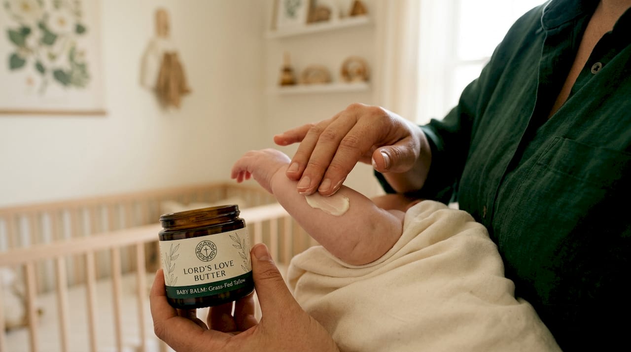 Parent applying tallow balm on baby's arm
