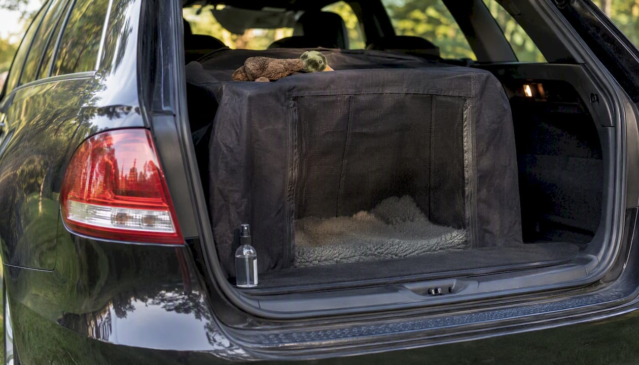Covered dog crate with calming spray in car boot