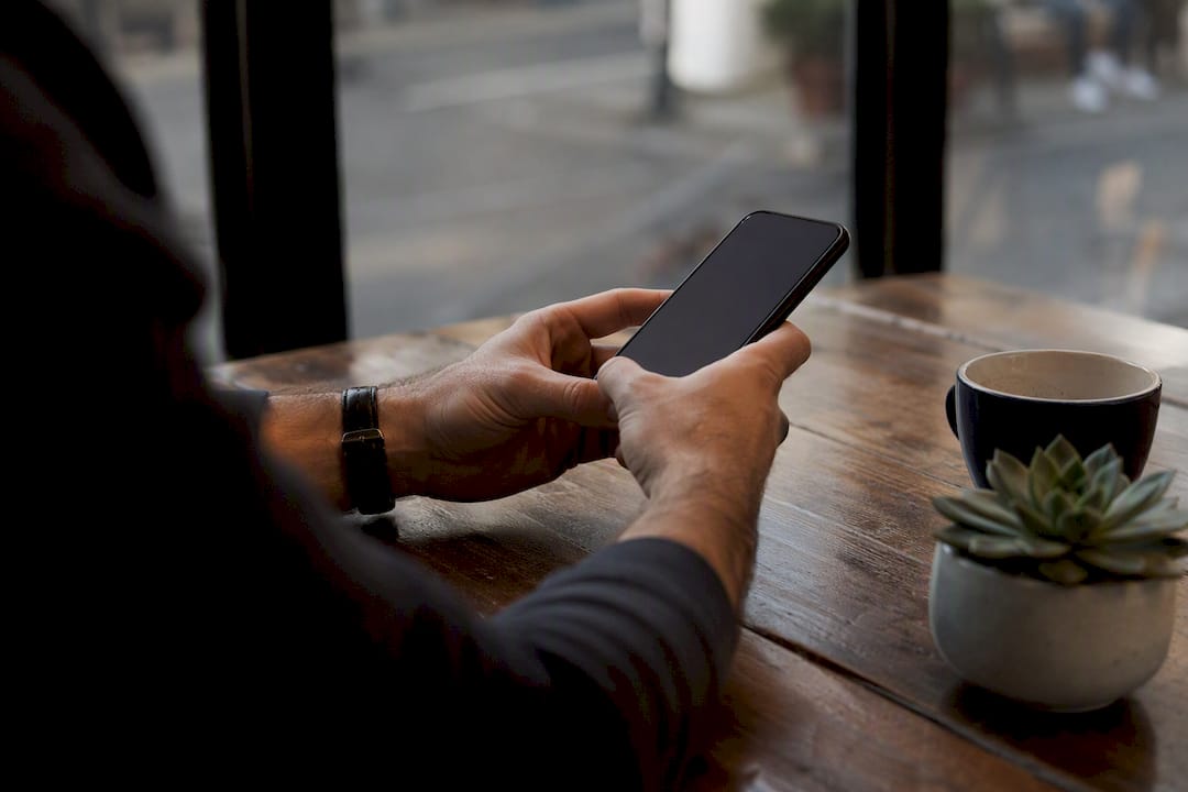 Founder hands holding smartphone in modern workspace