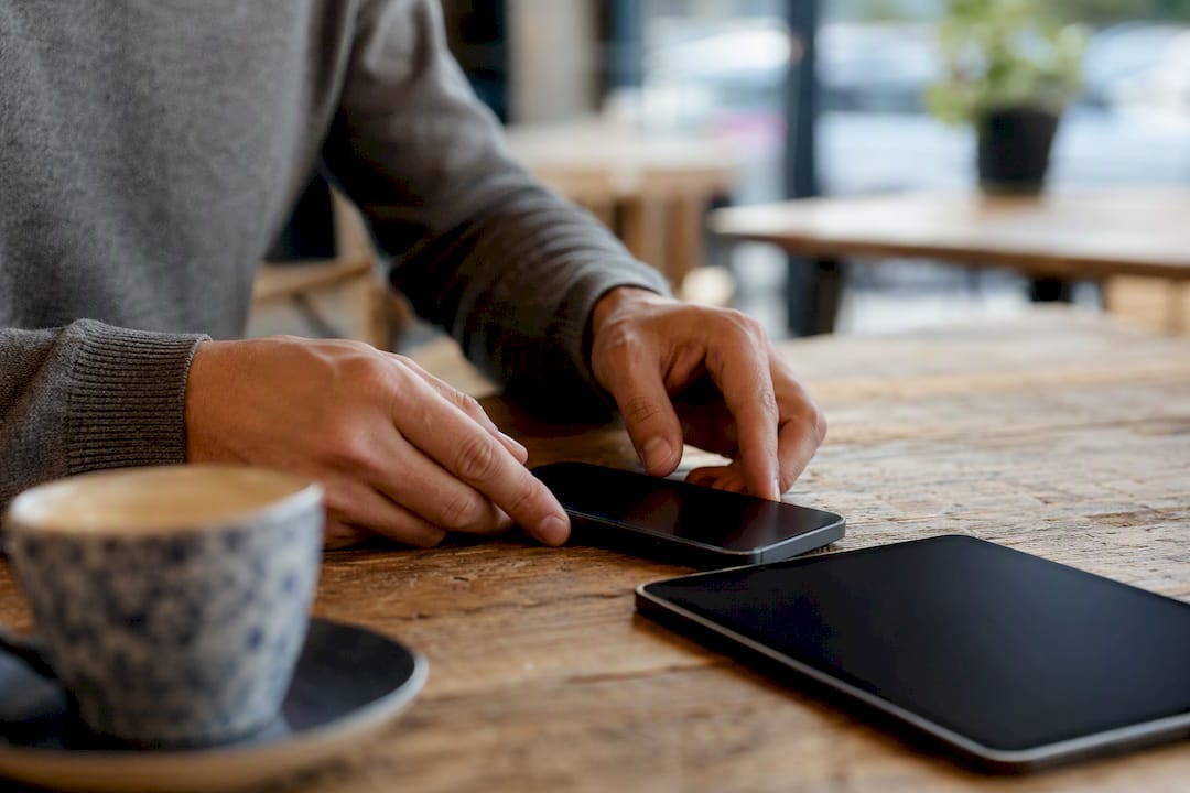 Hands arranging smartphone and tablet on desk