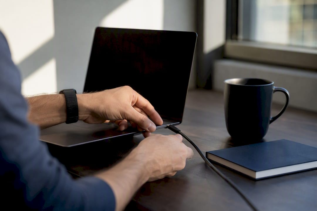 Hands connecting a charging cable on a tech desk