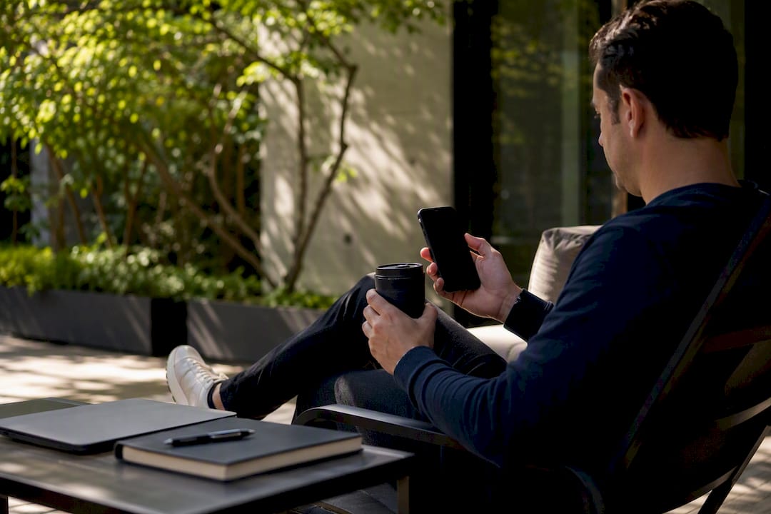 Founder holding dark phone and coffee mug